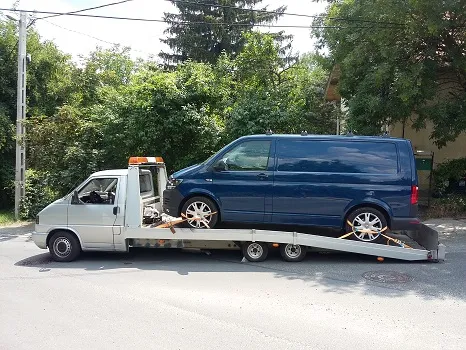 Sötétkék VW kisbusz felrakva az NSS platós autómentőre Budapesten